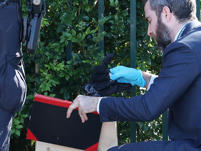 A detective bags evidence while conducting a line search outside Crawford Public School in Doonside on Saturday morning. Picture: Tim Hunter