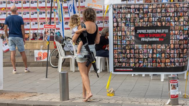 A mother walks near signs calling to bring the hostages home in Tel Aviv, Israel. While the Gazan missiles have been largely ineffective, thanks to Israel’s Iron Dome defence, they are adding to the trauma. Picture: Getty