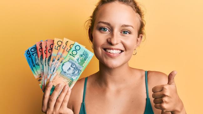 Young woman holding Australian dollars smiling happy and positive, thumb up doing excellent and approval sign; women female investing money generic