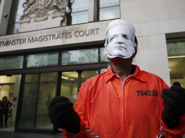 A supporter of WikiLeaks founder Julian Assange protests in front of a prison van entering Westminster Magistrates Court in London. Picture: AP Photo/Frank Augstein