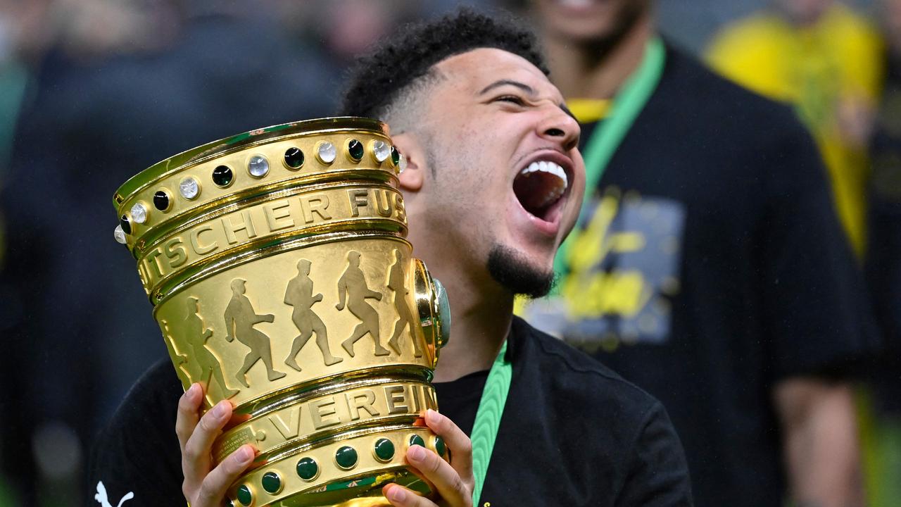 (FILES) In this file photo taken on May 13, 2021 Dortmund's English midfielder Jadon Sancho holds the trophy after winning the German Cup (DFB Pokal) final football match RB Leipzig v BVB Borussia Dortmund, in Berlin. - Manchester United have agreed a deal in principle to sign England winger Jadon Sancho from Borussia Dortmund according to media reports on June 30, 2021. (Photo by John MACDOUGALL / POOL / AFP) / RESTRICTIONS: ACCORDING TO DFB RULES IMAGE SEQUENCES TO SIMULATE VIDEO IS NOT ALLOWED DURING MATCH TIME. MOBILE (MMS) USE IS NOT ALLOWED DURING AND FOR FURTHER TWO HOURS AFTER THE MATCH. == RESTRICTED TO EDITORIAL USE == FOR MORE INFORMATION CONTACT DFB DIRECTLY AT +49 69 67880 /