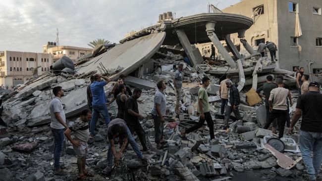 People search through buildings, destroyed during Israeli air strikes in the southern Gaza Strip on November 13. Picture: Getty Images