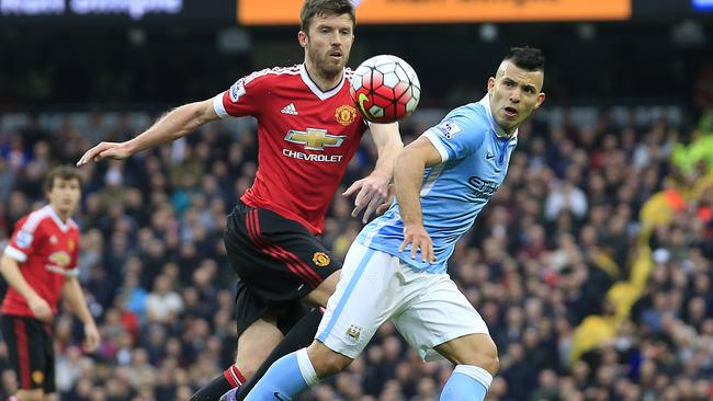 United’s Michael Carrick (L) and Manchester City's Sergio Aguero challenge for the ball.