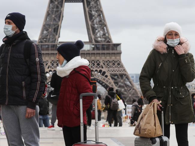 People wear protective face masks in front of the Eiffel Tower in Paris. Picture: AFP