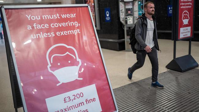 A man, not wearing a face covering, passes signs telling travellers they must wear face mask unless they are exempt, as he leaves London’s Victoria station. Picture: Tolga Akman/AFP