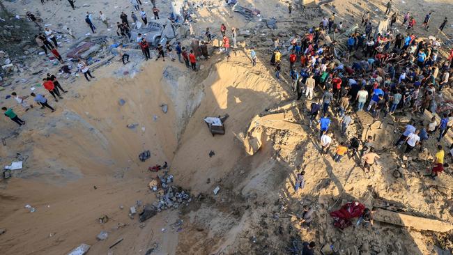 A crowd of Palestinian people gathers next to a crater caused by an explosion from an Israeli airstrike in Khan Yunis in the southern of Gaza Strip. Picture: AFP