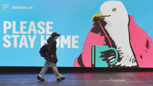 A woman walks past a sign urging people to stay home in Melbourne during the week. Picture: AFP