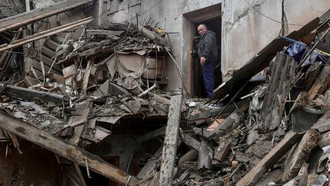 A local resident and a rescuer stand on debris of a museum hit by a Russian strike in Kupiansk on Tuesday. Picture: Reuters