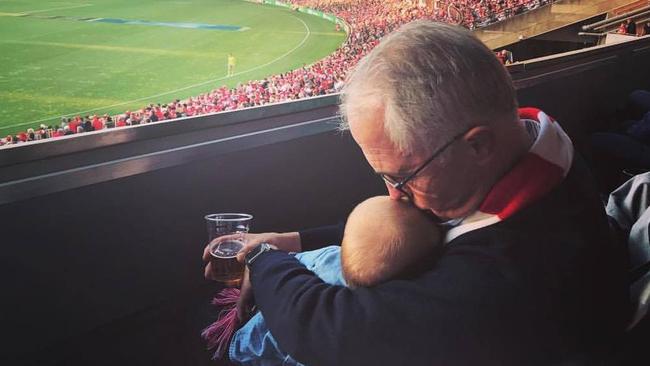 Prime Minister Malcolm Turnbull holds his granddaughter at the Swans v Essendon final at the SCG on Saturday.