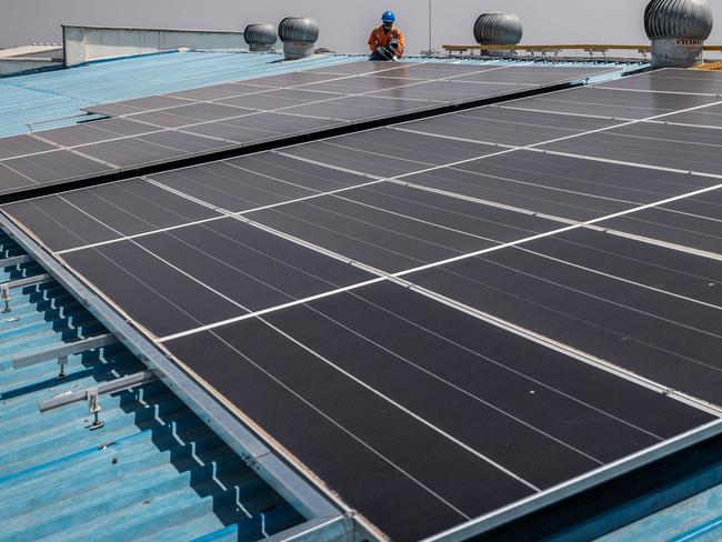 A technician from CP Solar walks on a roof during the installation of solar panels at a partially solar-powered factory in the industrial area of Nairobi, on October 9, 2023. Renewable energy sources generate over 80 percent of Kenya's electricity but despite the tremendous potential of the country's daily insolation, only 1% of the country's energy mix has been tapped. (Photo by LUIS TATO / AFP)