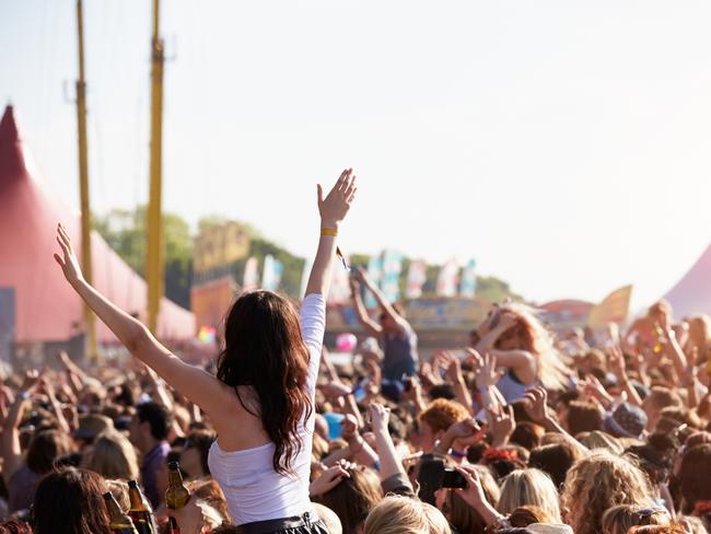 Crowds Enjoying Themselves At Outdoor Music Festival With Arms in The Air