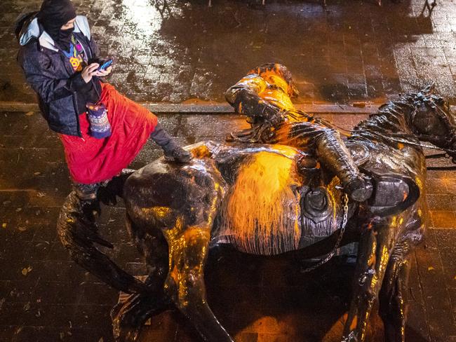 PORTLAND, OR - OCTOBER 11: A protester stands over a toppled statue of President Theodore Roosevelt during an Indigenous Peoples Day of Rage protest on October 11, 2020 in Portland, Oregon. Protesters tore down statues of two U.S. presidents and broke windows out of downtown businesses Sunday night before police intervened. (Photo by Nathan Howard/Getty Images)