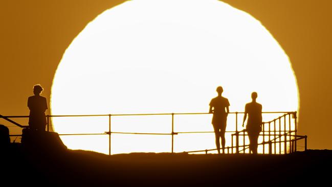 People watch as the sun rises over Ben Buckler Point in Bondi on Wednesday as Sydney sweltered in boiling hot weather. Picture: Getty Images