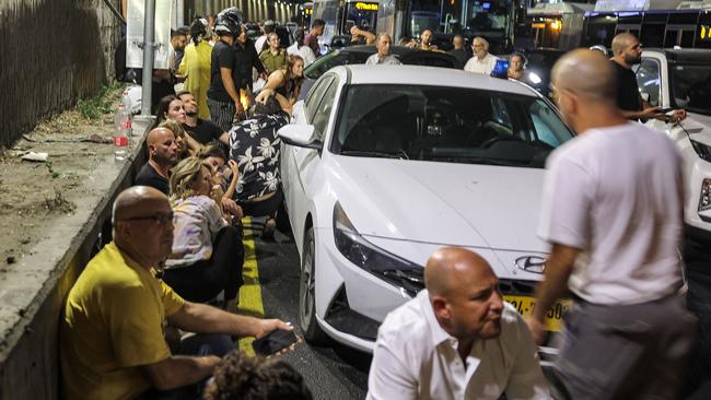 People take cover behind vehicles under a bridge along the side of a highway in Tel Aviv on October 1. Picture: Jack Guez/AFP