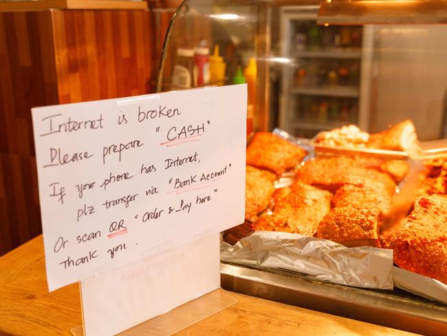 A sign asks customers to pay with cash or bank transfer at takeaway shop Xcelroll in Parramatta, one of countless businesses in Sydney which suffered losses due to the nationwide Optus outage this morning. Picture: Max Mason-Hubers