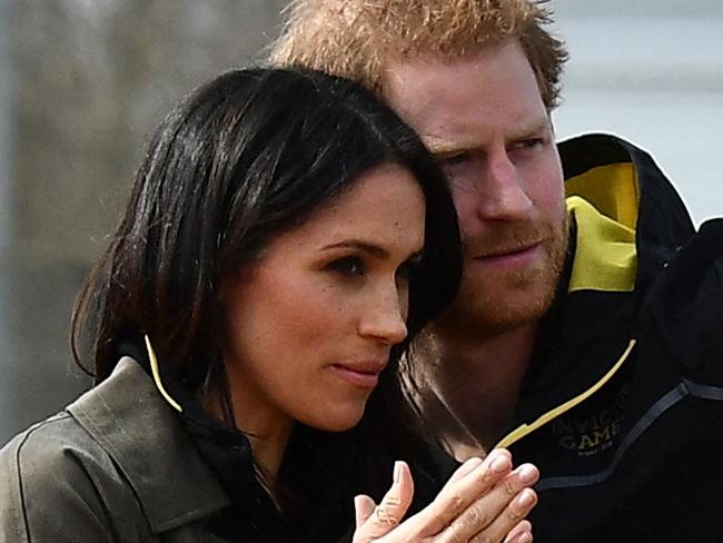 (FILES) In this file photo taken on April 6, 2018 Britain's Prince Harry (R) gestures to his fiancee US actress Meghan Markle (L) as they meet participants at the UK team trials for the Invictus Games Sydney 2018 at the University of Bath Sports Training Village in Bath, southwest England. - Meghan Markle has been "saddened" by reports published on Wednesday, March 3 that she faced a bullying complaint during her time at Kensington Palace and before she stepped back from royal duties, her spokesman said. (Photo by Ben STANSALL / AFP)