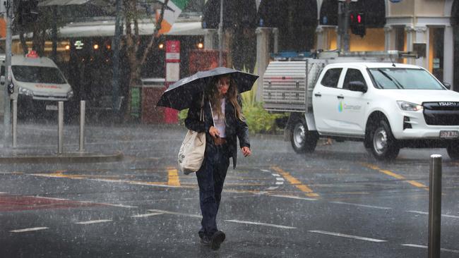 A young woman makes a run for it in the rain at Surfers Paradise on Friday morning. Picture: Glenn Hampson