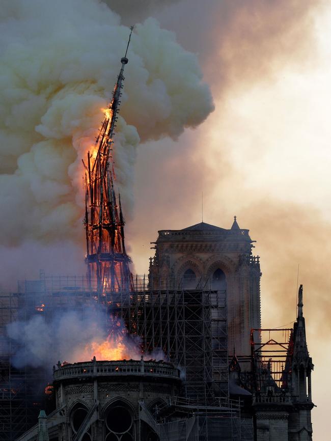 The steeple of the landmark Notre-Dame Cathedral collapses as the cathedral is engulfed in flames in central Paris on April 15, 2019. - A huge fire swept through the roof of the famed Notre-Dame Cathedral in central Paris on April 15, 2019, sending flames and huge clouds of grey smoke billowing into the sky. The flames and smoke plumed from the spire and roof of the gothic cathedral, visited by millions of people a year. A spokesman for the cathedral told AFP that the wooden structure supporting the roof was being gutted by the blaze. (Photo by Geoffroy VAN DER HASSELT / AFP)