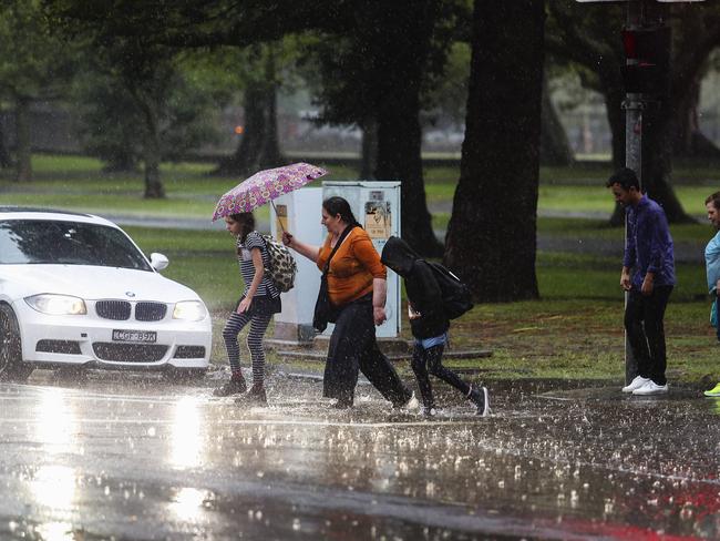 Pedestrians caught by the downpour at Lang Road, Moore Park. Picture: Justin Lloyd.