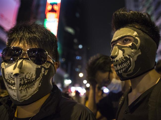 Masked protesters stand at the barriers dividing the police from the crowds in Mongkok, Hong Kong. Picture: Getty Images