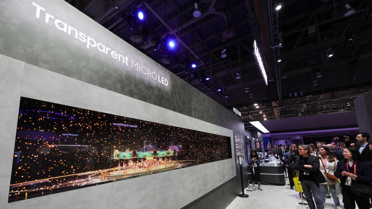 Attendees look at Samsung’s first transparent MicroLED display, shown in front of an LCD, giving it a 3D effect. Picture: Getty Images