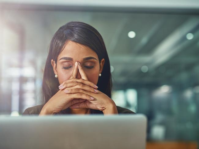 Shot of a young businesswoman looking stressed out while working in an office