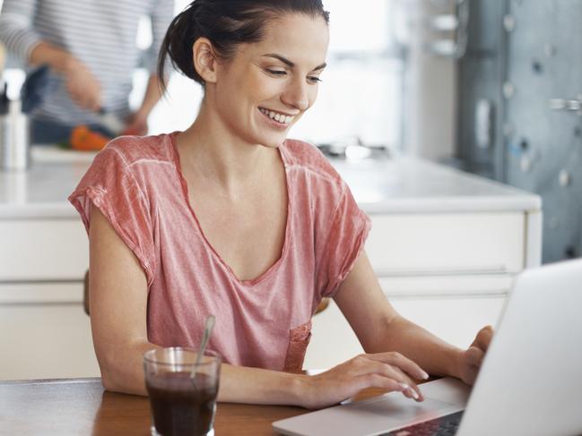 Generic shot of woman working on her laptop in the kitchen. Today's kitchens are more than just a food-prep zone, and have become spaces where we work and socialise. Free to use from iStock