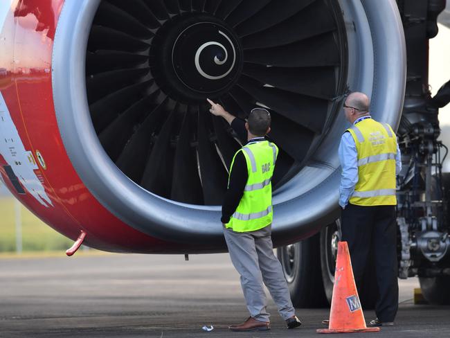 Safety Inspectors look over the engine of Air Asia flight D7207 at Brisbane Airport in Brisbane, Tuesday, July 4, 2017. An AirAsia flight from the Gold Coast has been forced back to Brisbane after a bird strike caused loud bangs and sparks to come from an engine. (AAP Image/Darren England) NO ARCHIVING.