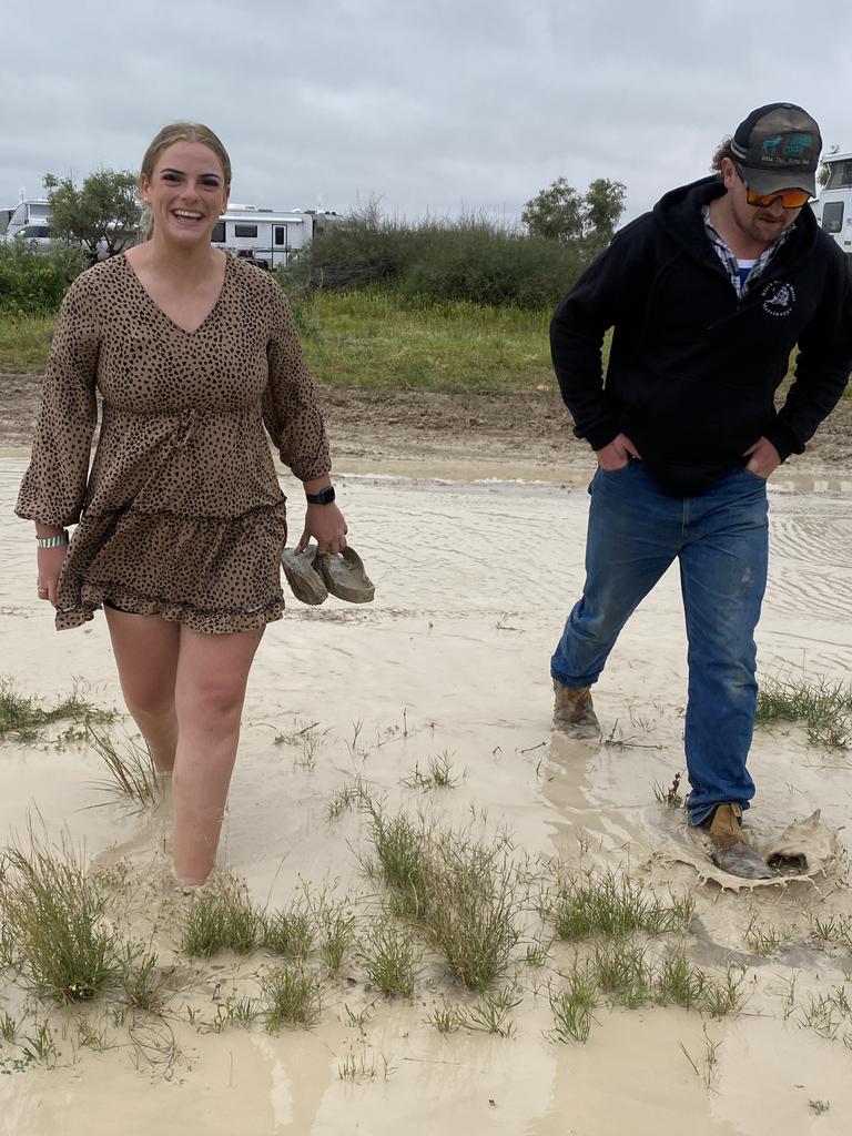 Abbie, from Darwin, and Ben from Yass venture through swamp-like campgrounds to their site.