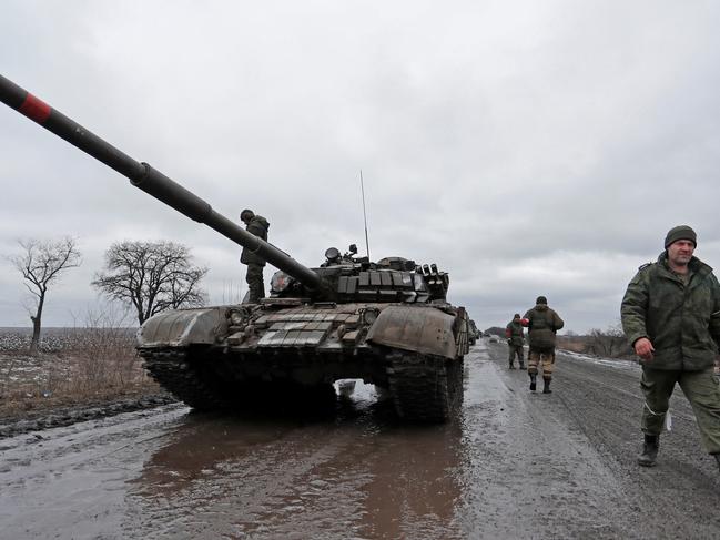 Servicemen of pro-Russian militia walk next to a military convoy of armed forces of the separatist self-proclaimed Luhansk People's Republic on a road in the Luhansk region. Picture: Reuters