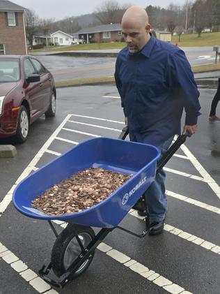 Nick Stafford rolls in the first of five wheelbarrows full of change. <i>Picture: David Criggeru</i>