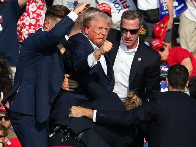 Donald Trump is surrounded by secret service agents as he is taken off the stage at a campaign event in Pennsylvania after he was shot. Picture: Rebeccar Droke/AFP