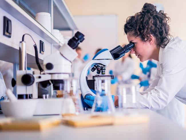 Scientist in lab doing research and using lab machines, test tubes, microscope and every laboratory equipment