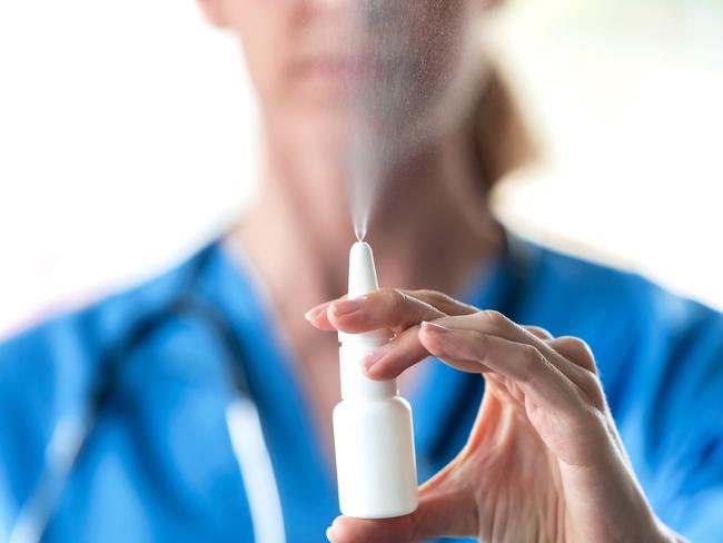 Close-up of female doctor with a spray or nasal drops for the treatment of a runny nose over white background.