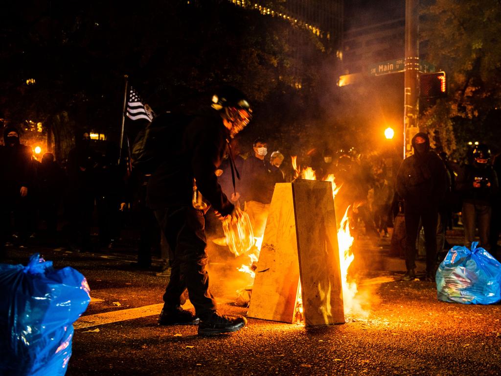 Protesters light a fire in front of the Mark Hatfield Justice Center in Portland, protester continued vote counting. Picture: Kathryn ELSESSER / AFP