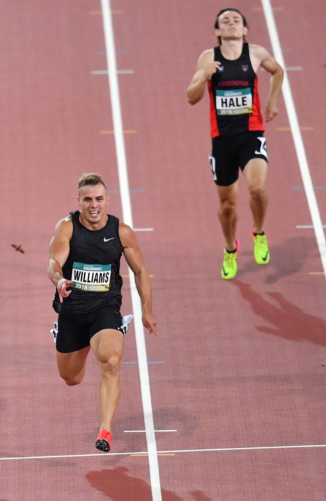 Trae Williams (left) of Queensland in action winning the men's 100 metres final as Jack Hale (right) of Tasmania pulls up injured.