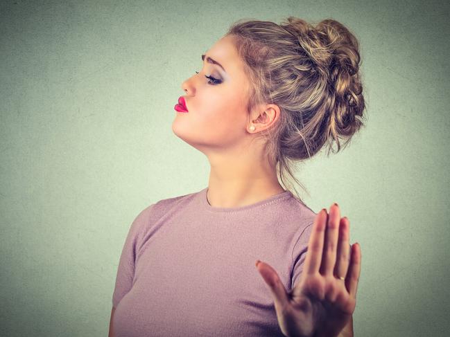 Snobby young annoyed angry woman with bad attitude giving talk to hand gesture with palm outward isolated grey wall background. Negative human emotion face expression feeling body language