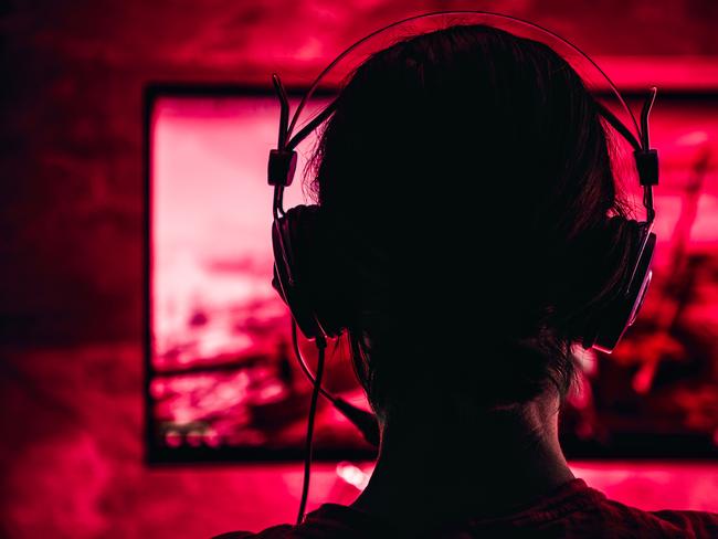 Woman wearing headphones playing video games late at night. Video games, gaming, screen time, kids and technology, headphones, generic