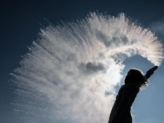 A woman tosses hot water into the freezing cold air that is immediatly turned into a sparkling cloud of snow on March 1, 2018 in Berlin. Picture: AFP