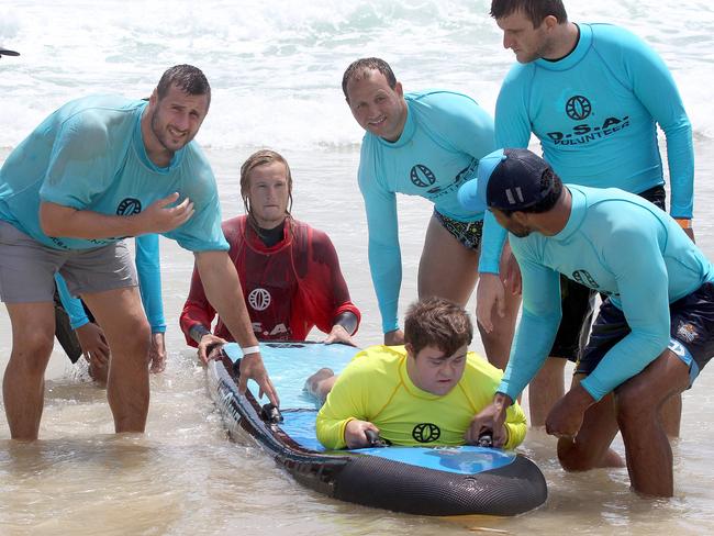 Titans players Alex Gerrard (left) Tyrone Roberts (centre) and Kallum Watkins (front right) with Disabled Surfing Association participant Aaron Bathgate. Picture: Mike Batterham