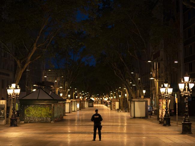 A Catalan police officer stands in the middle of a deserted Las Ramblas in Barcelona. Picture: AP.