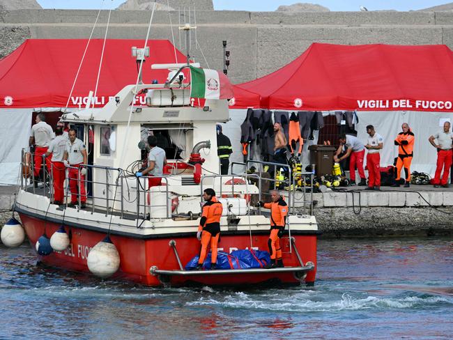 Divers of the Vigili del Fuoco, the Italian Corps. of Firefighters arrive in Porticello harbor near Palermo, with a third body at the back of the boat on August 21, two days after the British-flagged luxury yacht Bayesian sank. Picture: Alberto Pizzoli / AFP