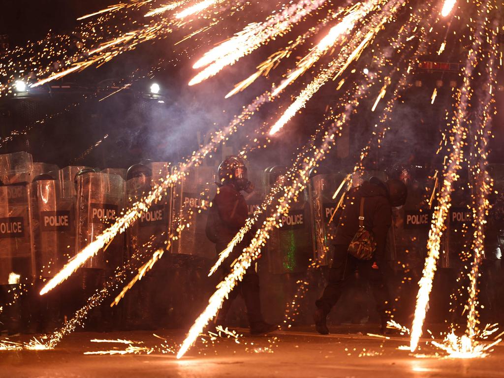 Police stand in a rain of exploding fireworks outside the Parliament building. Picture: Giorgi ARJEVANIDZE / AFP