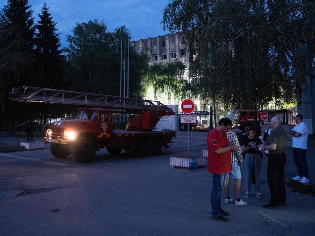 Local residents wait outside a military educational facility fore news. Picture: AFP.