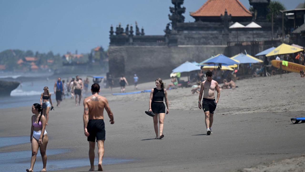 Tourists walk on a beach in Canggu, Badung regency on Bali island. Picture: SONNY TUMBELAKA / AFP.