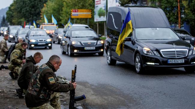 Ukrainian troops kneel beside the hearse, carrying their fallen brother-in-arms Armen Petrosian, who was killed fighting the Russians.