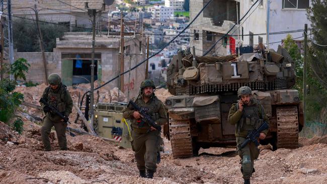 Israeli soldiers walk behind a tank at the Jenin camp for Palestinian refugees in the occupied West Bank during a military operation on February 24. Picture: AFP