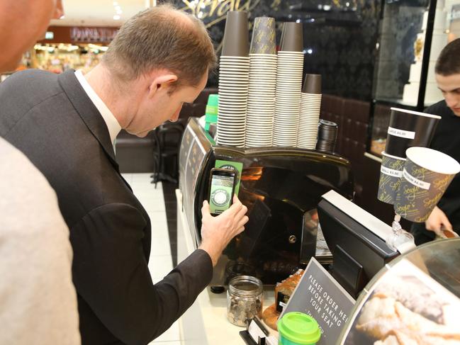 Inner West mayor Darcy Byrne scanning his Green Caffeen app at the Sergio’s Cake Shop.