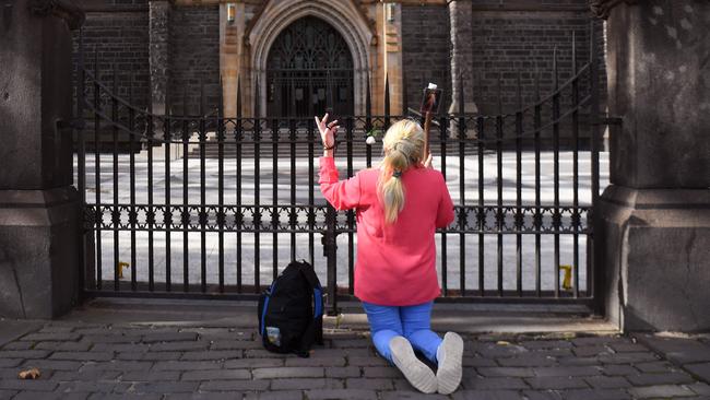 A woman prays outside St Patrick's Catholic Cathedral on Good Friday in Melbourne as churches closed to the public live stream their Easter services due to the COVID-19 coronavirus pandemic. Picture: William West/AFP