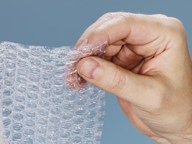 Man holding a roll of plastic bubble wrap.